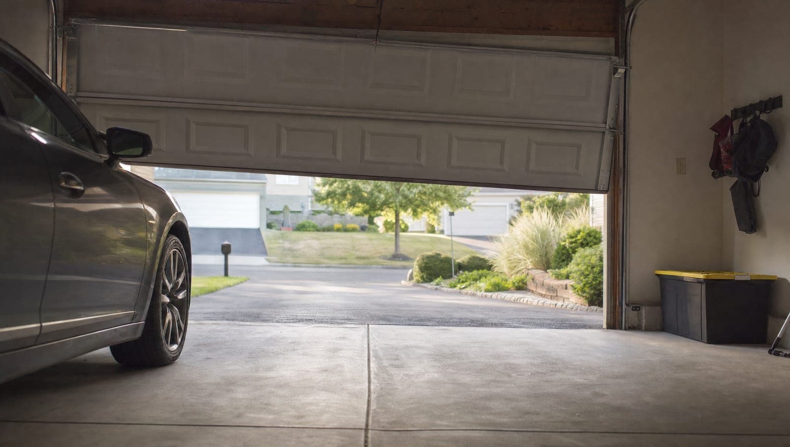 Residential two-car garage door stuck partway open and slightly crooked in a suburban driveway