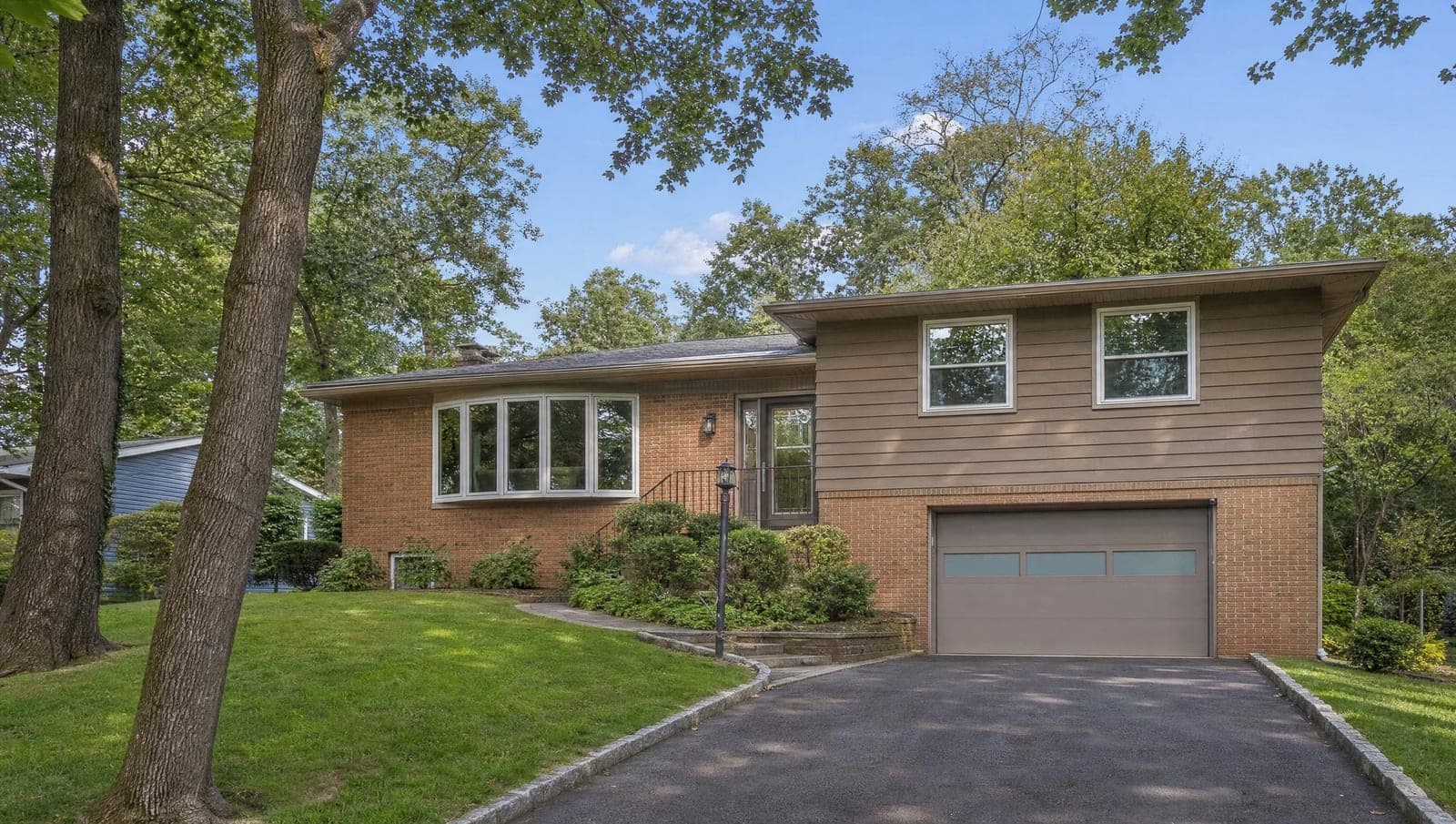 1950s North Jersey split-level home with a clean flush-panel single garage door and a horizontal frosted window row